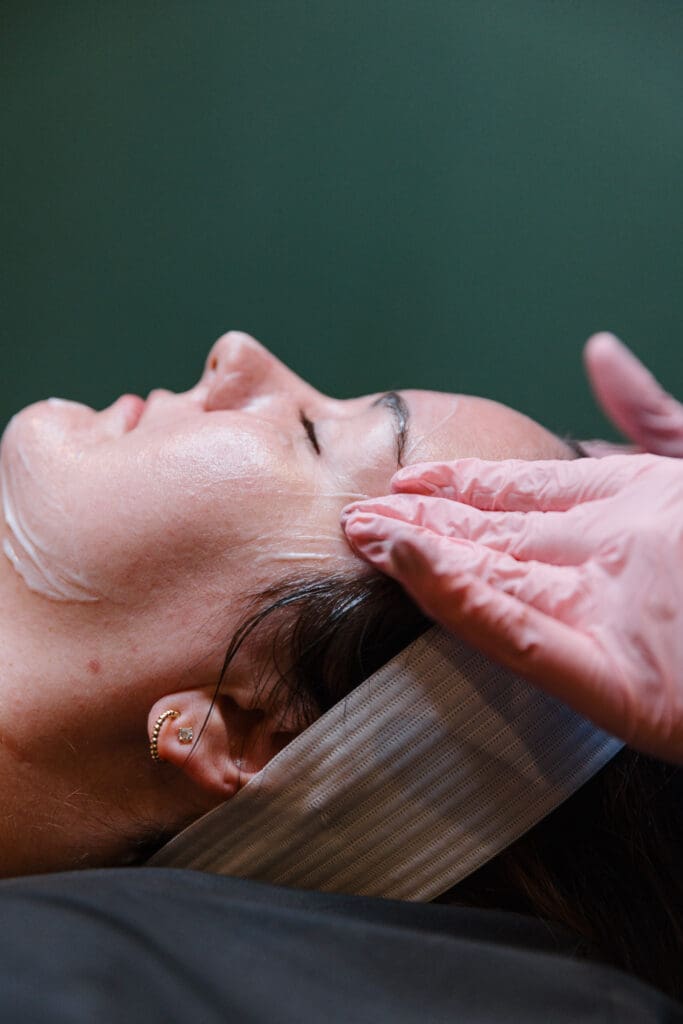 Woman getting facial by hands in pink gloves