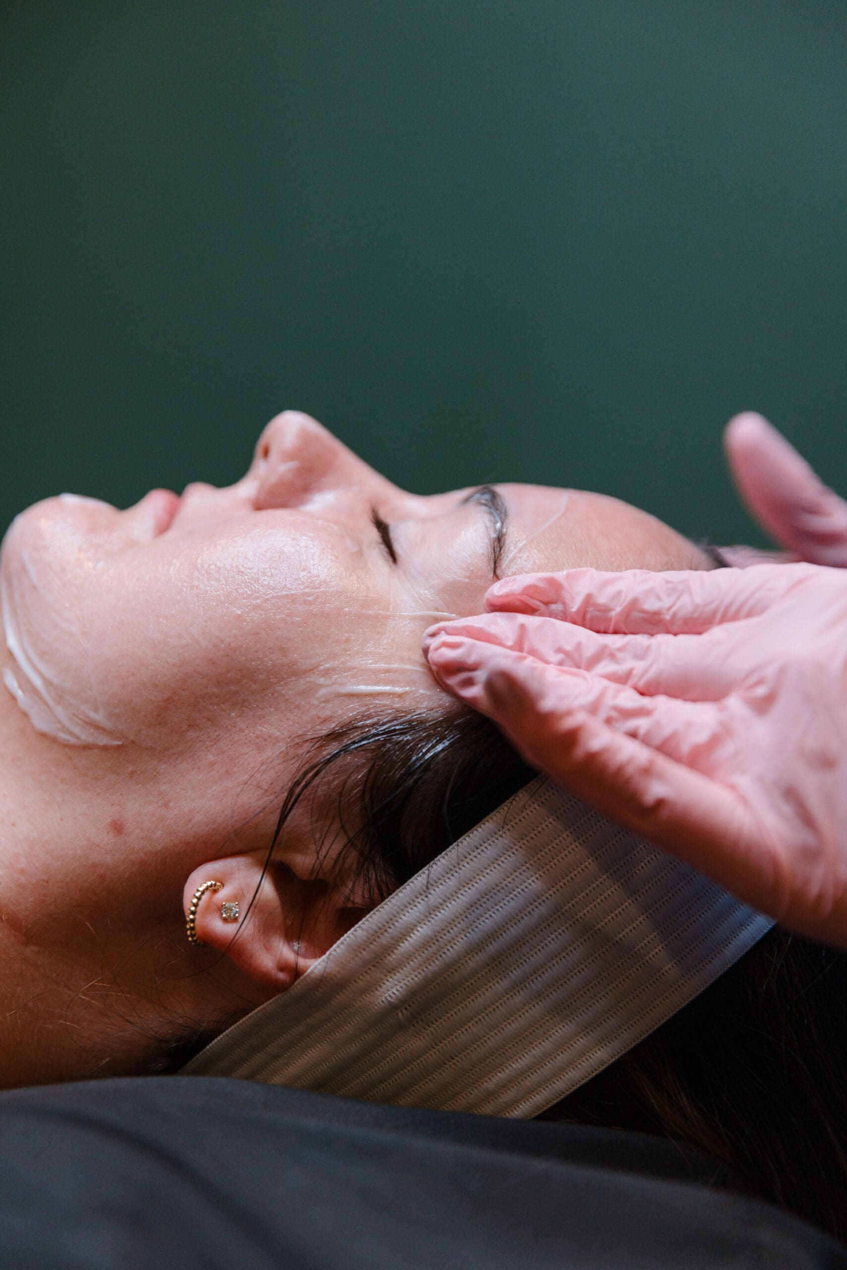 Woman getting facial by hands in pink gloves